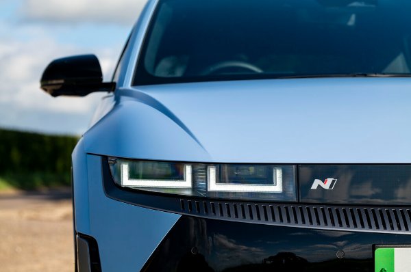 Close-up of a car's front-view showing headlights and a logo on the bonnet.