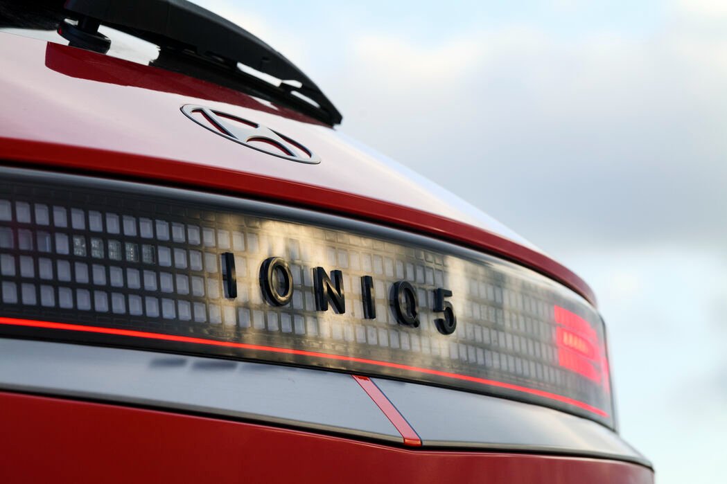 Close-up of IONIQ 5 badge on a red car's rear with Hyundai logo above.