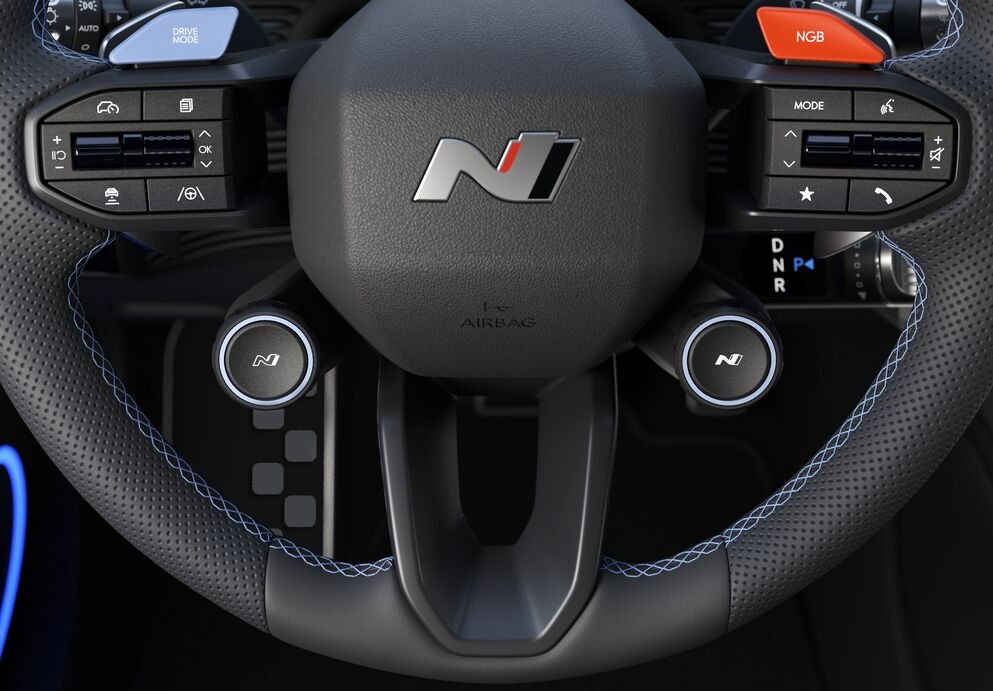Steering wheel with buttons and blue stitching, featuring a logo in the centre.