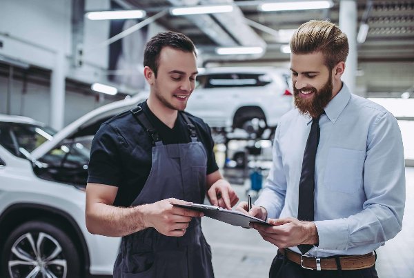 two man signing in front of a car